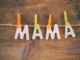 The word Mama spelled out in wooden letters in front of a wooden background
