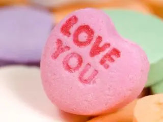 Closeup of a candy heart with the words LOVE YOU on it