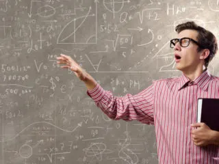 Funny nerdy young man working on an impossible math problem on a chalkboard