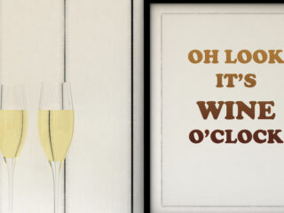 Two glasses of white wine next to a sign that reads Oh Look It's Wine O' Clock