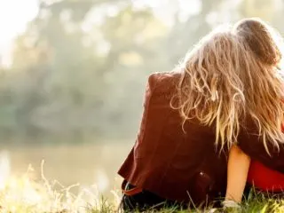 Female best friends sitting in the grass looking at the scenery