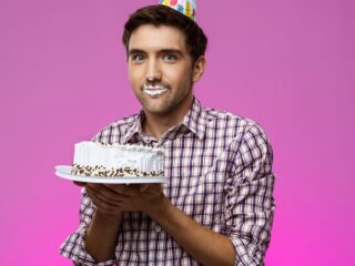 Silly guy holding a birthday cake with frosting on his lips